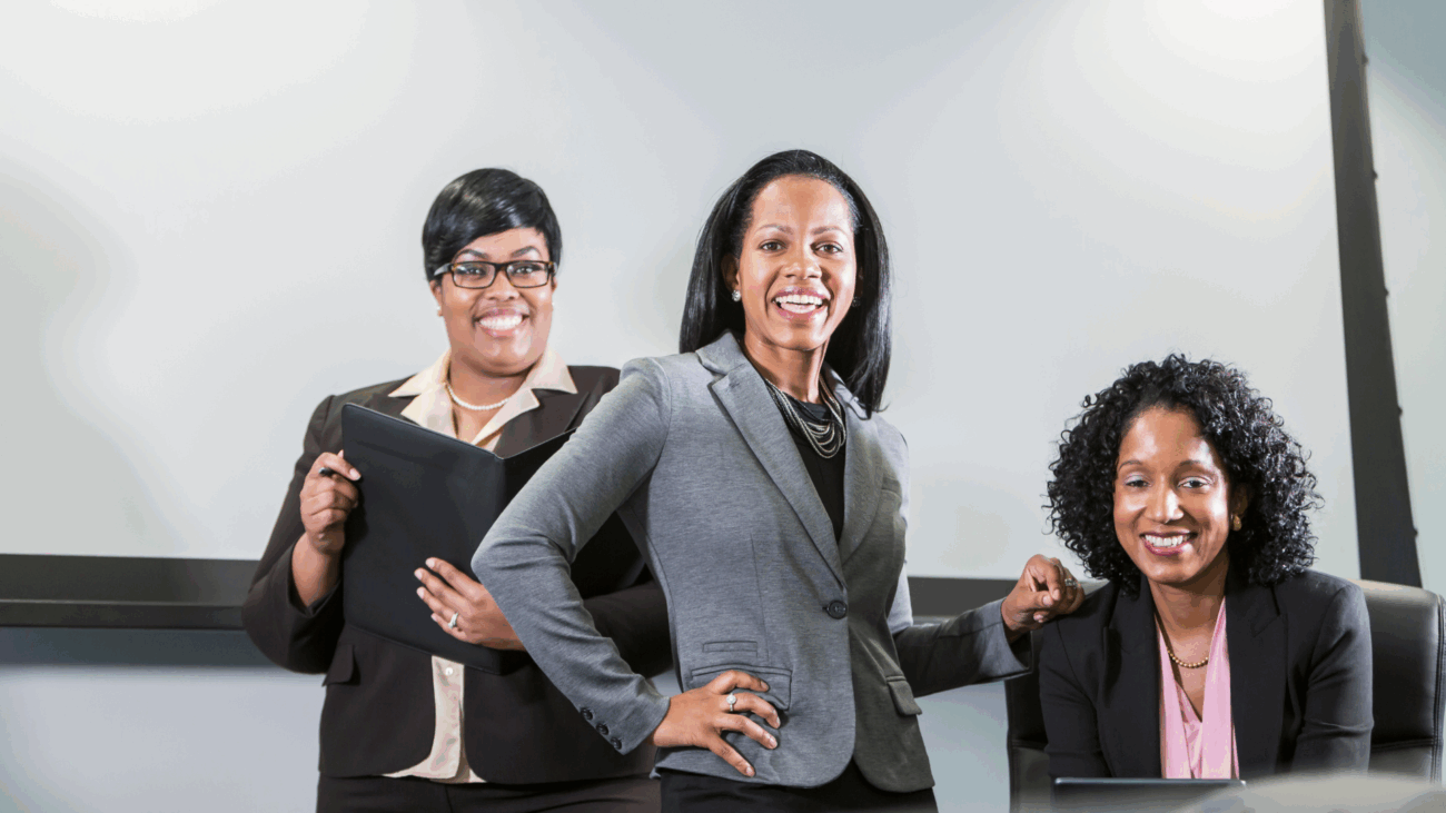 Three businesswomen standing confidently in front of a presentation screen, promoting a marketplace for Black-owned businesses.